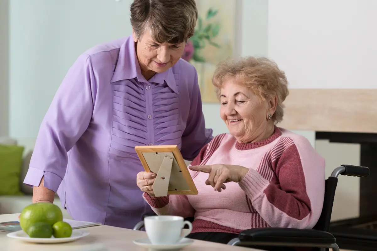 Elderly woman looking at a family photo during transition to memory care at Carefield Pleasanton
