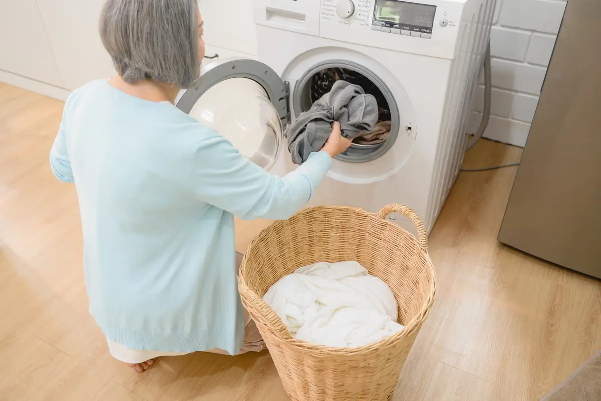 Senior Woman Doing Laundry | Activities of Daily Living | Carefield Castro Valley Senior woman independently managing laundry, one of the instrumental activities of daily living supported at Carefield Castro Valley