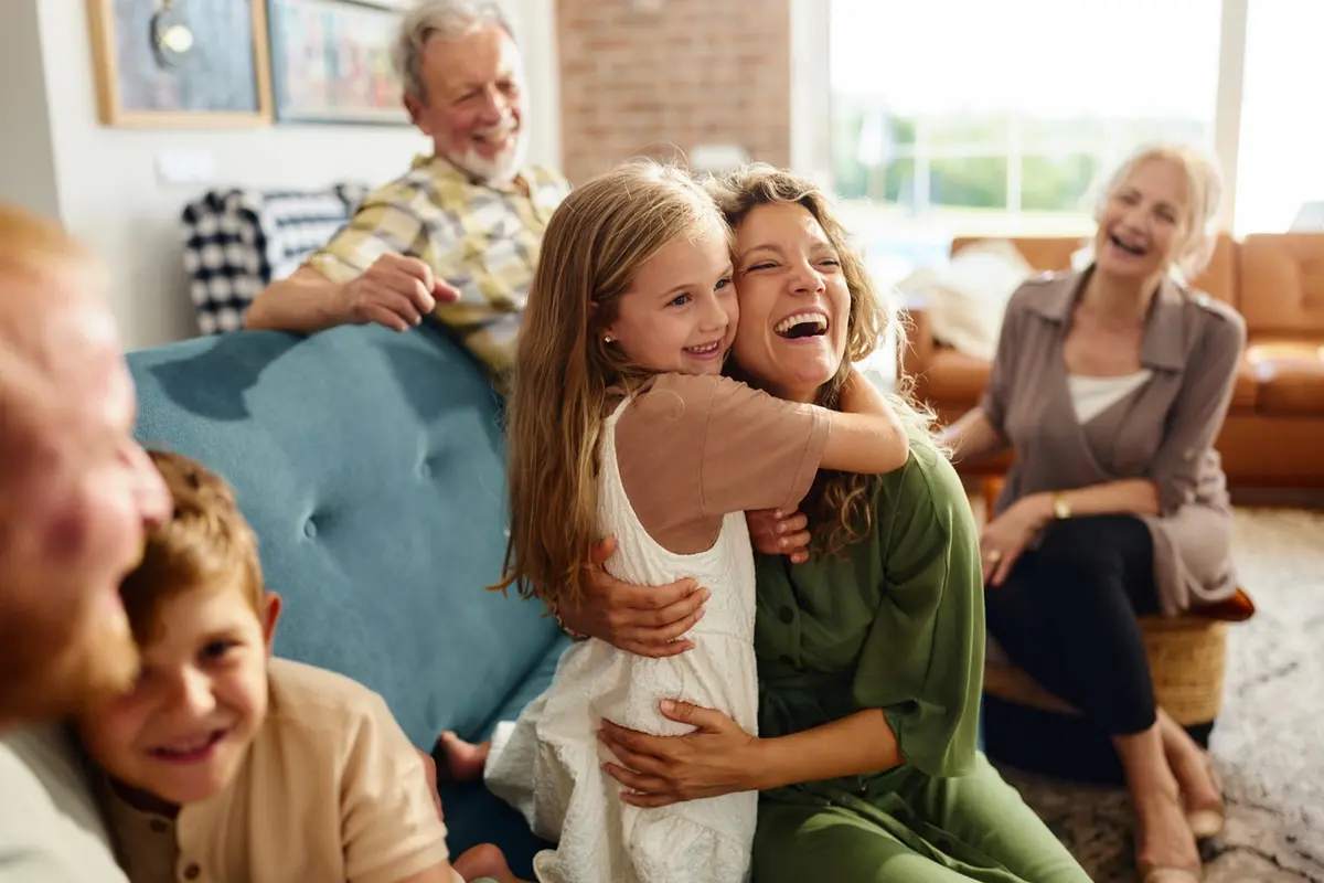 A mother and daughter embrace warmly at home, representing the emotional reconnection and family healing that supports caregiver PTSD recovery after the prolonged stress of caring for a loved one with dementia.