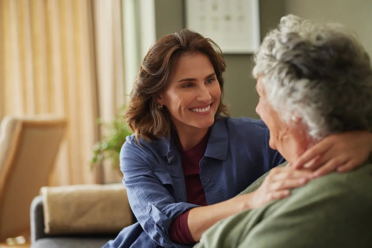 Adult daughter embracing elderly mother in memory care showing family involvement at Carefield Park Visalia