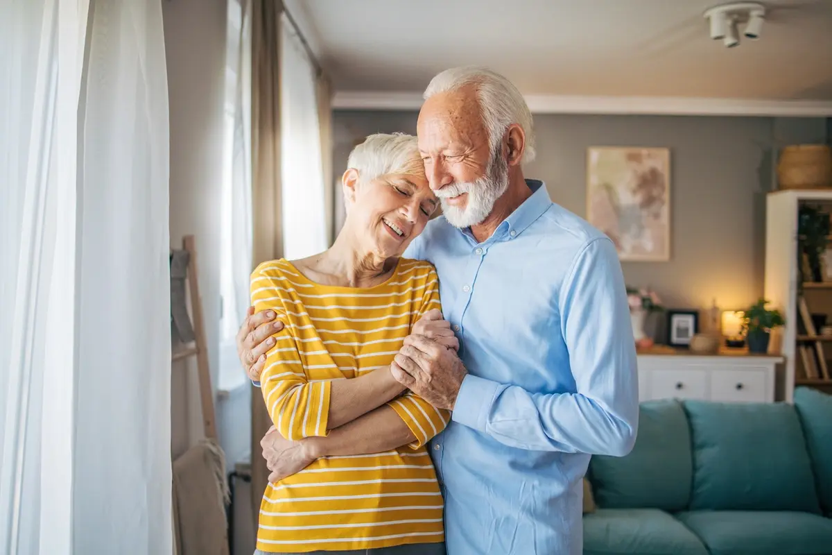 Senior couple in living room smiling and bonding while experiencing early signs of memory loss