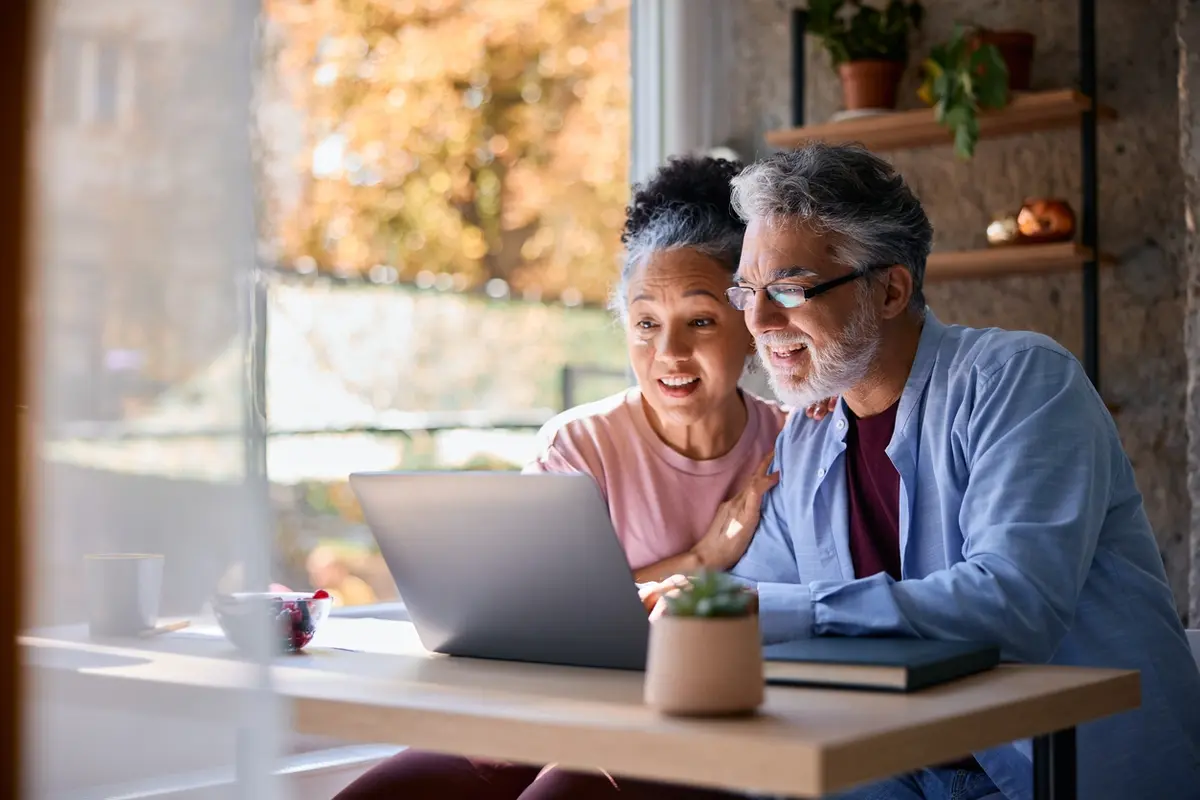 A senior couple looks surprised while reviewing information on memory care community, representing families learning tips for choosing a memory care facility that fits their loved one's needs.