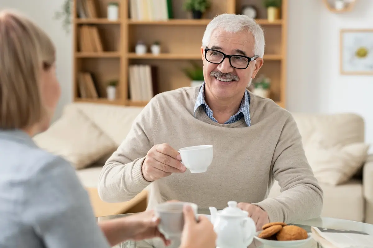 Senior father holding a cup of tea while talking with his daughter about the stages of dementia and when to consider memory care