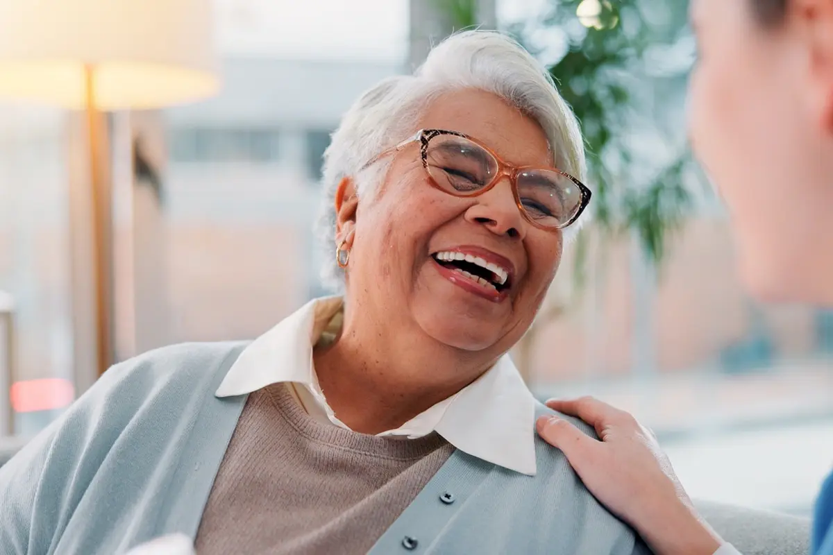 Older woman laughing with a caregiver, showing the benefits of moving to assisted living early at Carefeld Park Visalia