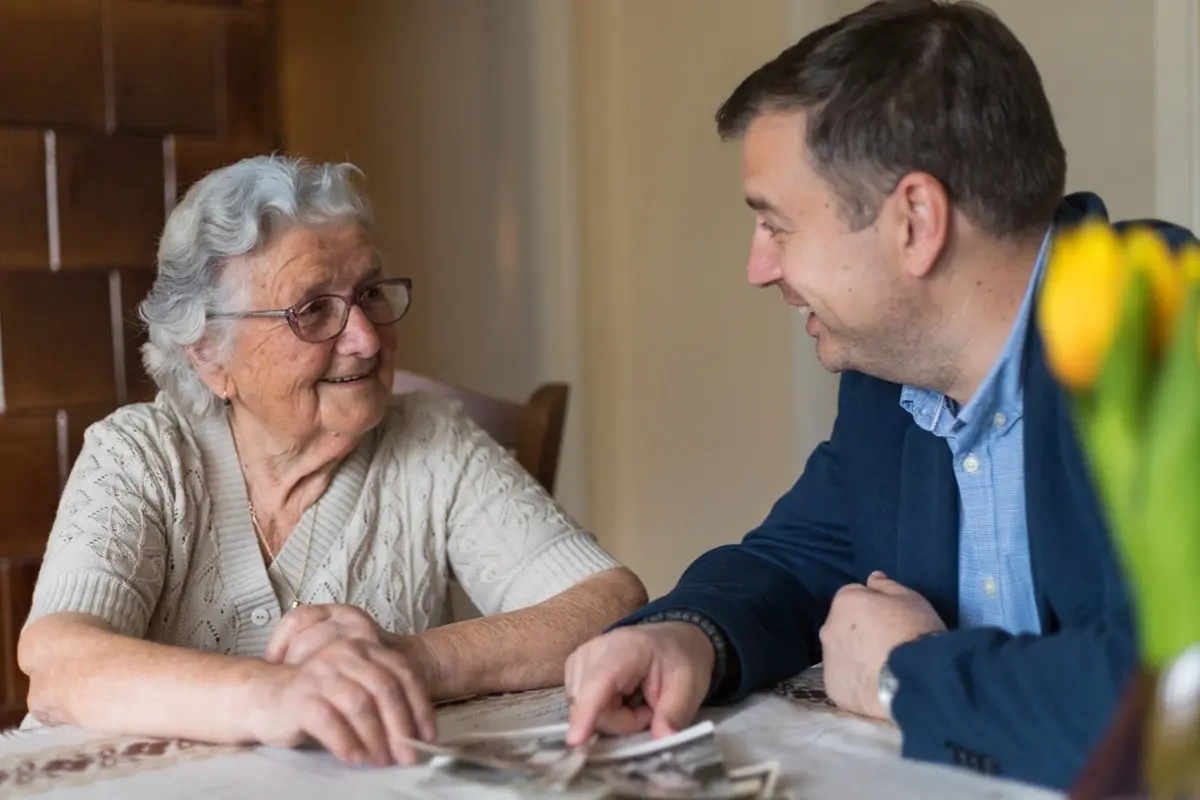 Senior man smiling with friends, showing the value of caregiver consistency in memory care in Carefield Castro Valley