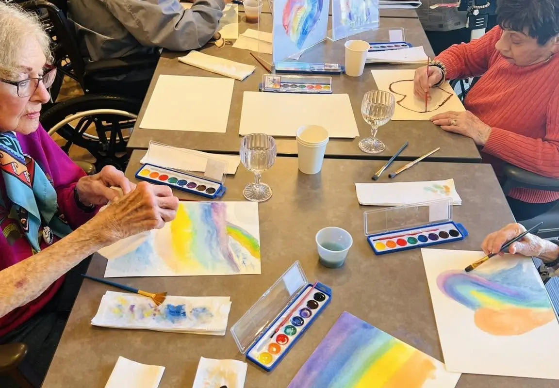 Older adults participating in a watercolor painting activity at an assisted living and memory care community.