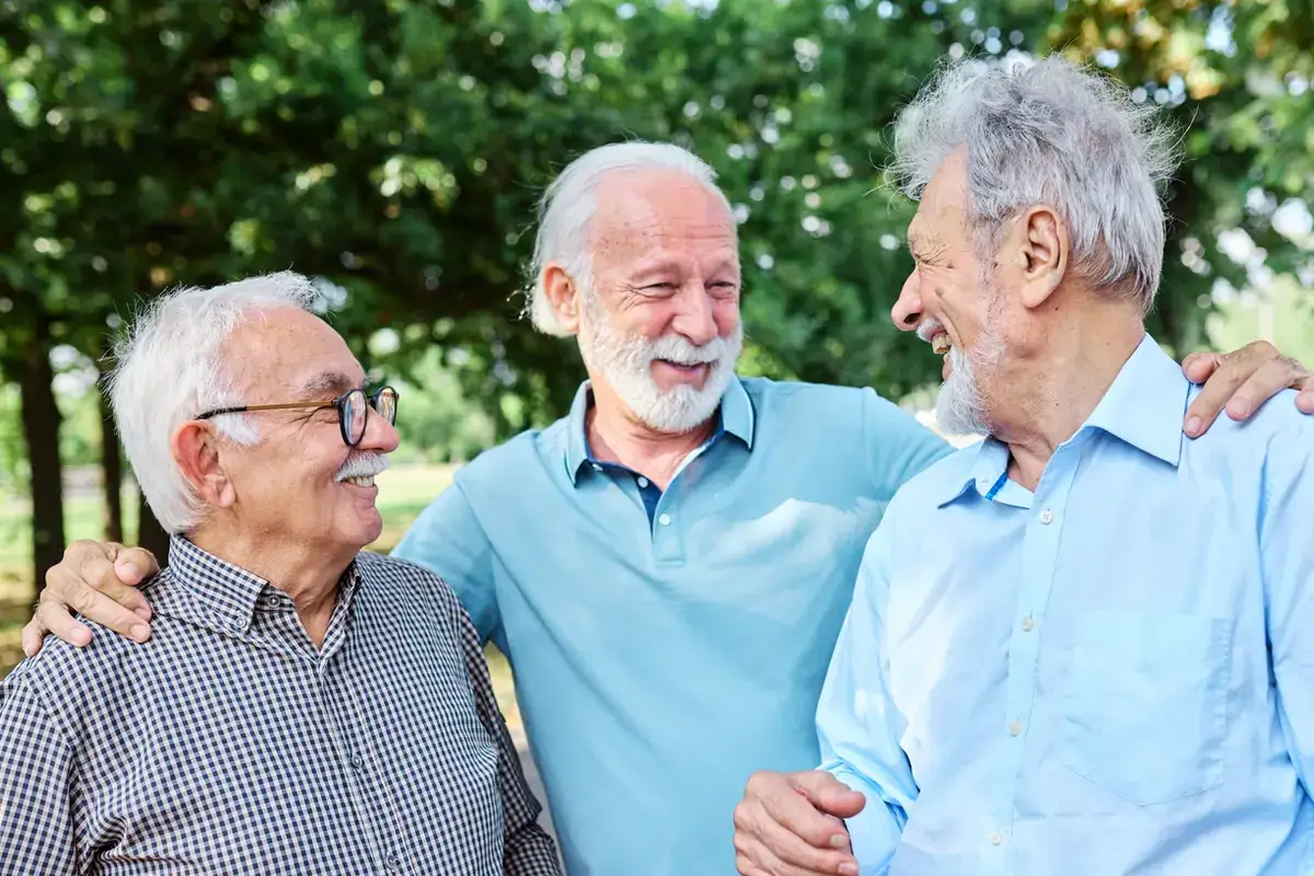 Three senior men smiling and conversing outdoors at a memory care community in Ojai.