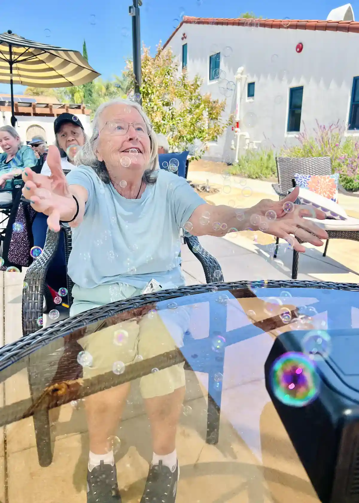 A resident enjoying outdoor bubble activities at Ojai Meadows Senior Living, illustrating the transition from home ownership to senior living.