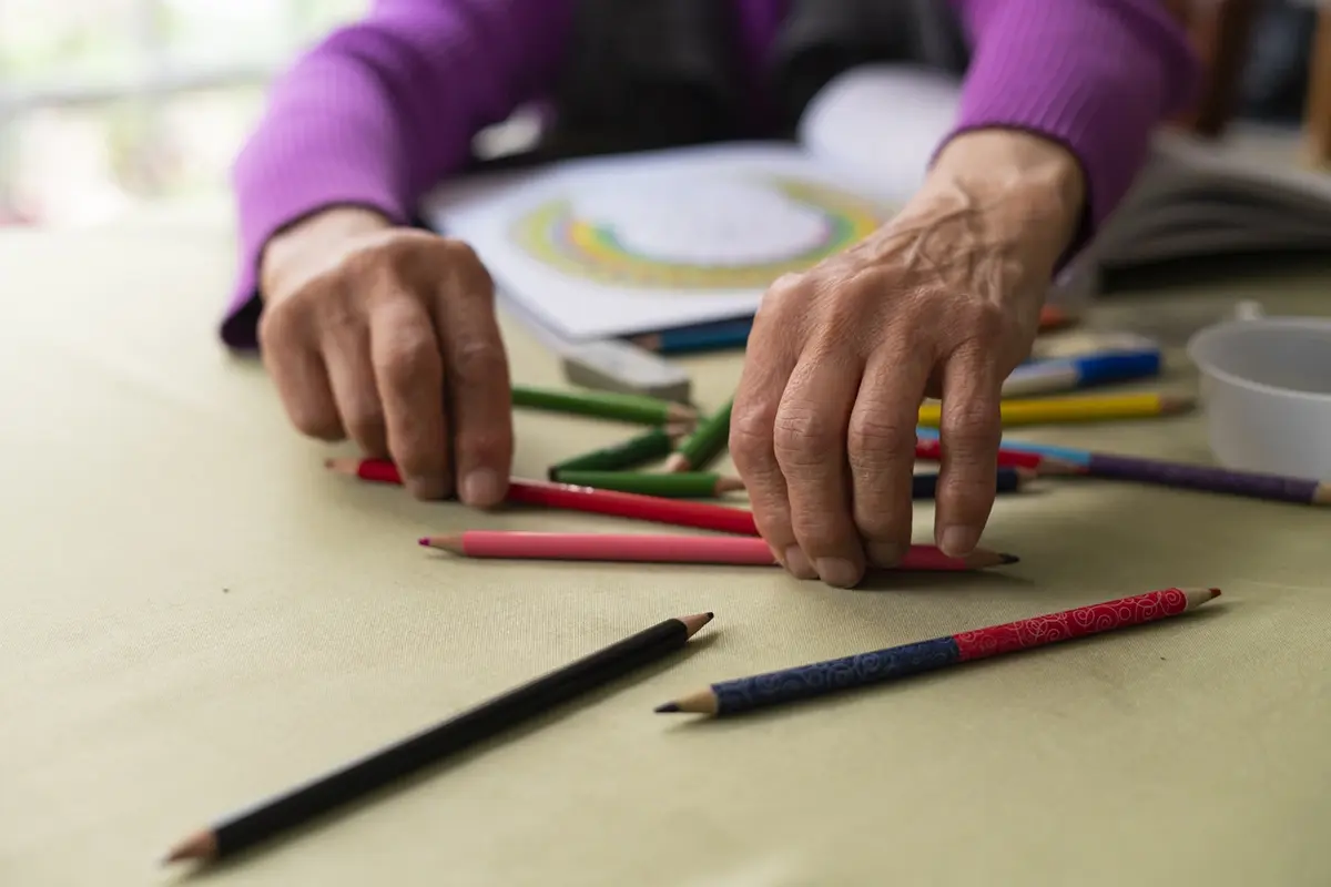 sorting-crayons-hands-close-up-fine-motor-skills Close-up of a memory care Pleasanton resident sorting crayons by hand during a fine motor skills activity